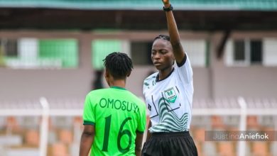 Omotoye Oluwatosin issuing a yellow card to a player during a competitive women's football match