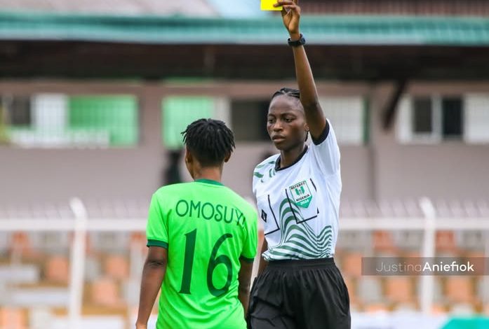Omotoye Oluwatosin issuing a yellow card to a player during a competitive women's football match