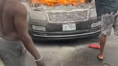 A burnt car on 3rd Mainland Bridge in Lagos, showing bystanders working to extinguish the fire.