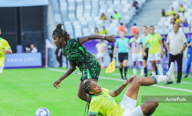 Esther Okoronkwo, dressed in the green and white jersey of the Super Falcons, controls the ball during an intense match, showcasing her composure and focus.