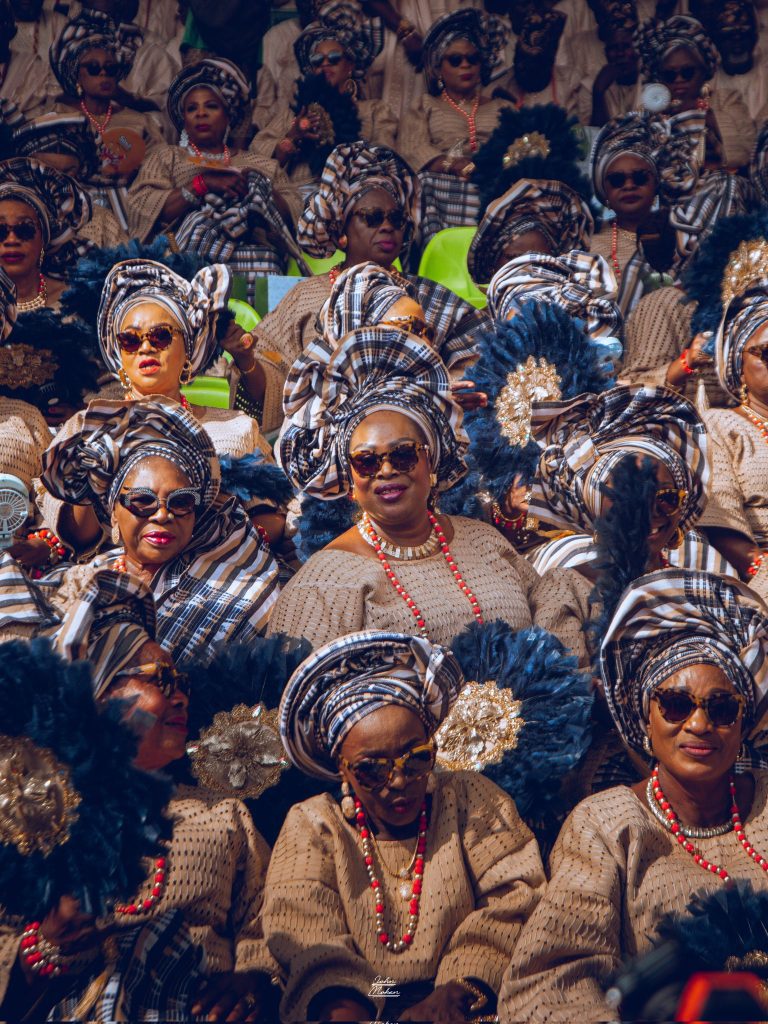 Elegant Yoruba women in vibrant iro and buba ensembles with matching gele, seated gracefully and attentively watching the cultural festivities at the Ojude Oba Festival 2025 in Ijebu-Ode, Ogun State, Nigeria.