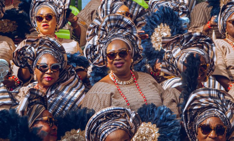 Elegant Yoruba women in vibrant iro and buba ensembles with matching gele, seated gracefully and attentively watching the cultural festivities at the Ojude Oba Festival 2025 in Ijebu-Ode, Ogun State, Nigeria.