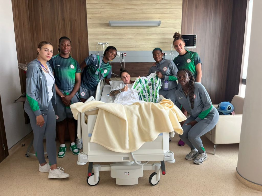 WAFCON 2024: Gabriela Salgado lies in a hospital bed smiling as Rasheedat Ajibade and Super Falcons teammates present her with a signed Nigeria national team jersey.