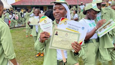 Amina Aminu Mohammed, NYSC corps member in Ibadan North, holding her Certificate of National Service and an award plaque after the 2025 Passing Out Parade