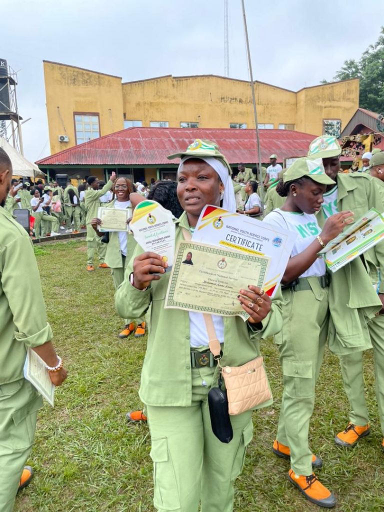 Amina Aminu Mohammed, NYSC corps member in Ibadan North, holding her Certificate of National Service and an award plaque after the 2025 Passing Out Parade