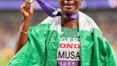 Tobi Amusan celebrates her silver medal at the Tokyo 2025 World Athletics Championships with the Nigerian flag draped around her neck.